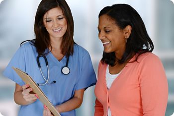 This is a picture of a nurse showing a patient a paper on a clipboard.